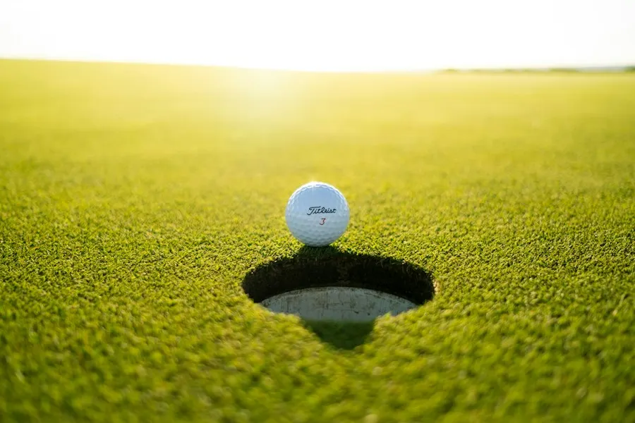 Representative golf ball beside a putting green cup